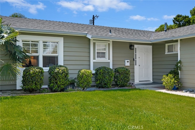 view of front of property featuring a front lawn and roof with shingles