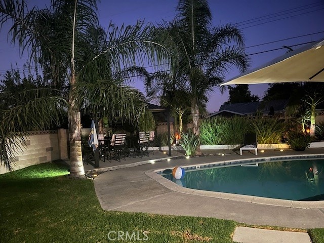 pool featuring a lawn, fence, and a patio area