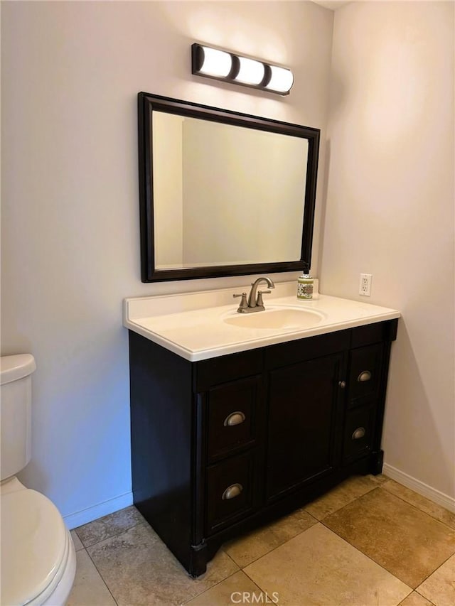 bathroom with baseboards, tile patterned flooring, toilet, and vanity