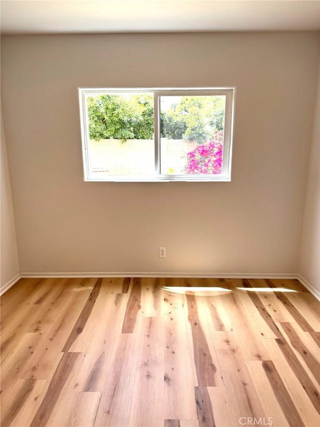 empty room featuring baseboards and light wood-type flooring