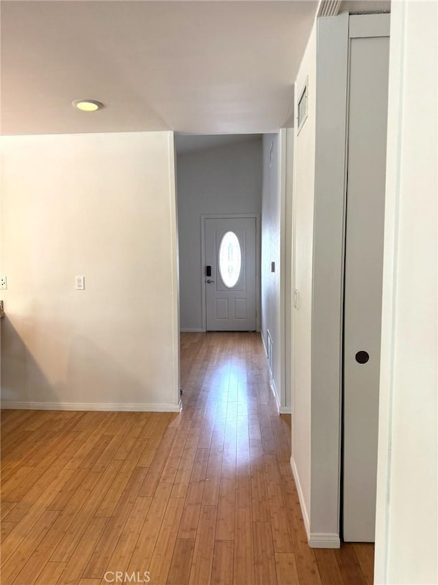 corridor with baseboards, light wood-style flooring, and visible vents