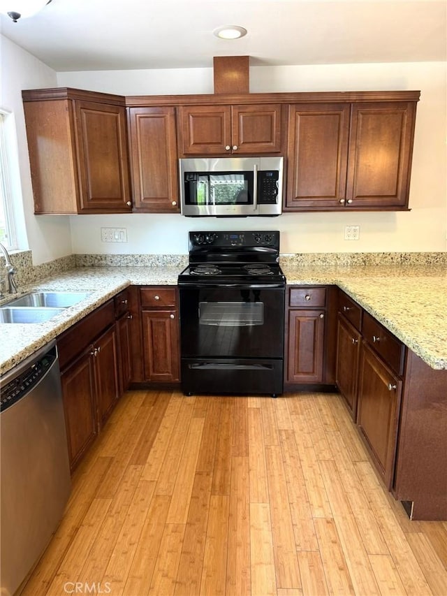 kitchen with light stone countertops, recessed lighting, a sink, light wood-style flooring, and stainless steel appliances