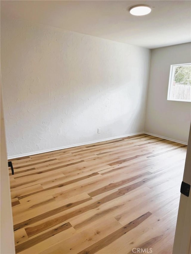 spare room featuring baseboards and wood finished floors