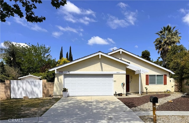 view of front of home with concrete driveway, a garage, fence, and stucco siding