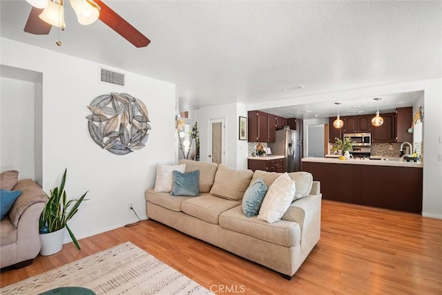 living area featuring ceiling fan, visible vents, and light wood-style floors