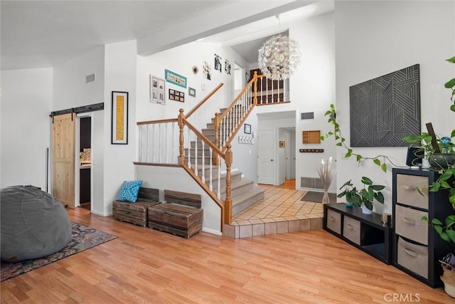 interior space with high vaulted ceiling, visible vents, a barn door, and wood finished floors
