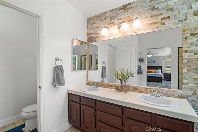 ensuite bathroom featuring a sink, baseboards, ensuite bath, and double vanity