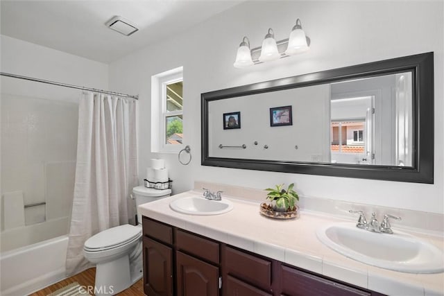 bathroom featuring double vanity, toilet, shower / bath combination with curtain, and a sink