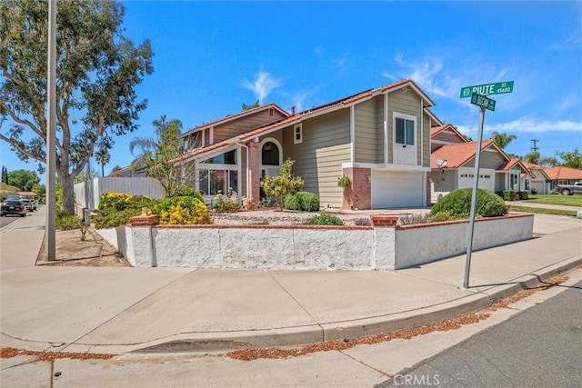 view of front facade featuring concrete driveway, brick siding, fence, and a garage