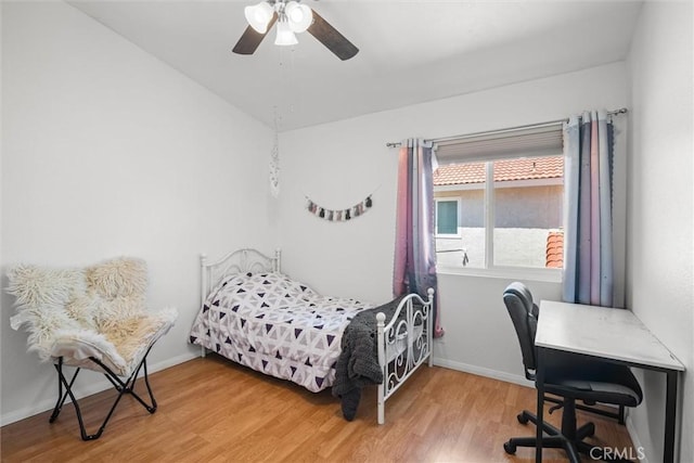bedroom with a ceiling fan, baseboards, and light wood-type flooring
