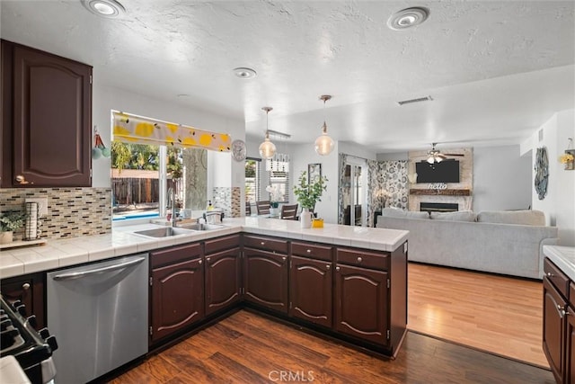 kitchen featuring a sink, tile countertops, dishwasher, and a fireplace