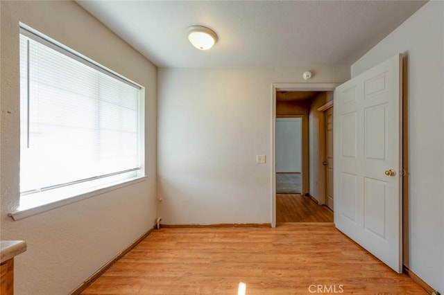 unfurnished room featuring baseboards and light wood finished floors
