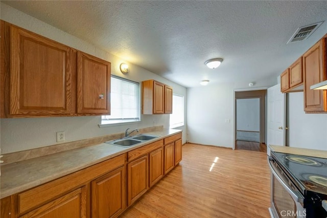 kitchen featuring a sink, brown cabinets, a textured ceiling, and visible vents