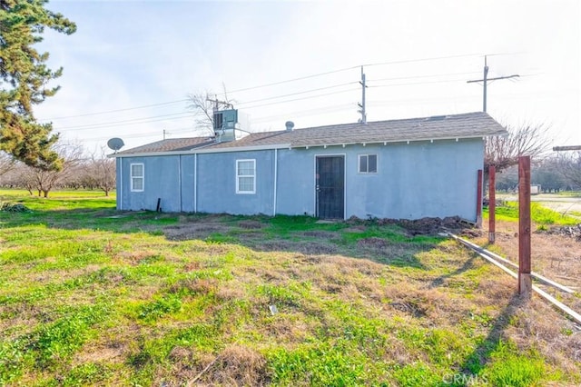 back of house with a lawn, central air condition unit, and stucco siding