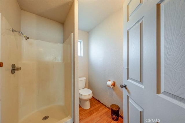 full bathroom with a shower stall, toilet, and wood finished floors
