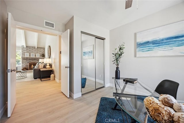 18128 Cari Ln, Yorba Linda, CA 92886 - home office with a ceiling fan, visible vents, baseboards, a warm lit fireplace, and light wood-style flooring