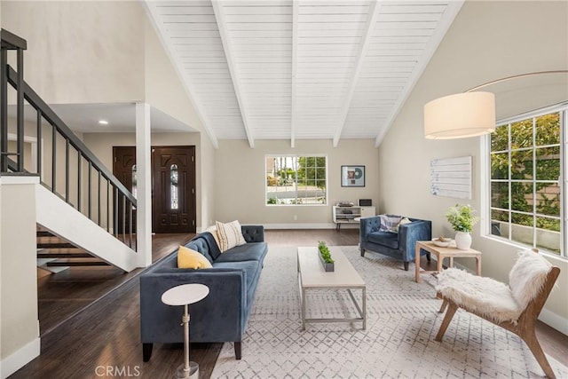 living room with wood finished floors, baseboards, beamed ceiling, and stairs