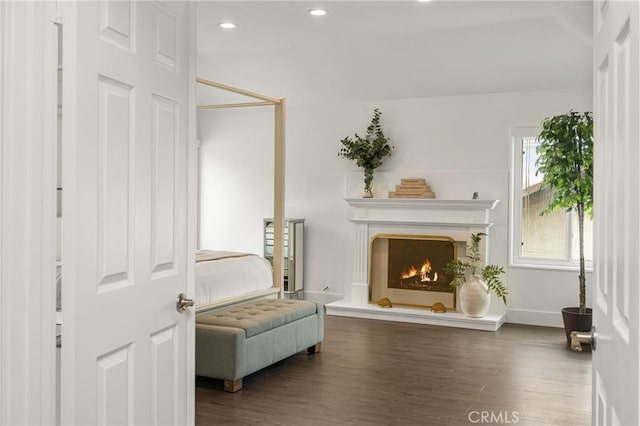 living area with a lit fireplace, recessed lighting, baseboards, and wood finished floors