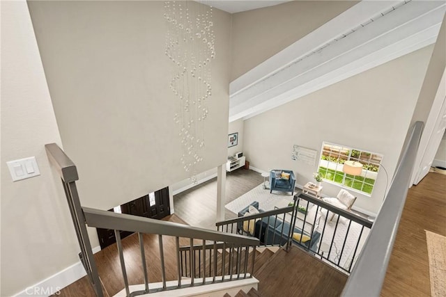 stairway featuring wood finished floors, baseboards, and a towering ceiling