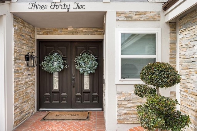 doorway to property with stone siding and brick siding