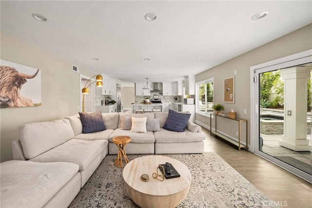 living area with visible vents, light wood-style flooring, and recessed lighting