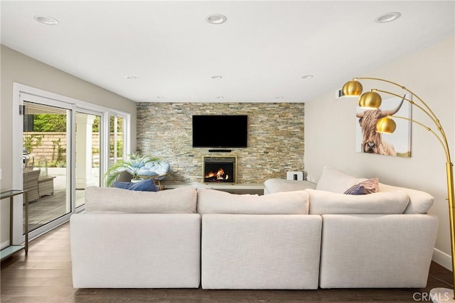living room featuring wood finished floors, a stone fireplace, and recessed lighting