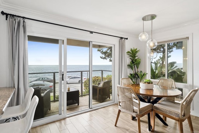 dining area with crown molding, a water view, and light wood-style flooring