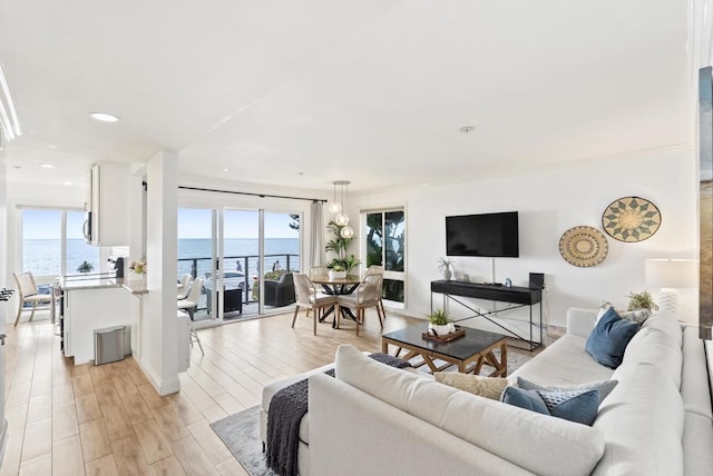 living area with light wood-style floors, a water view, baseboards, and recessed lighting