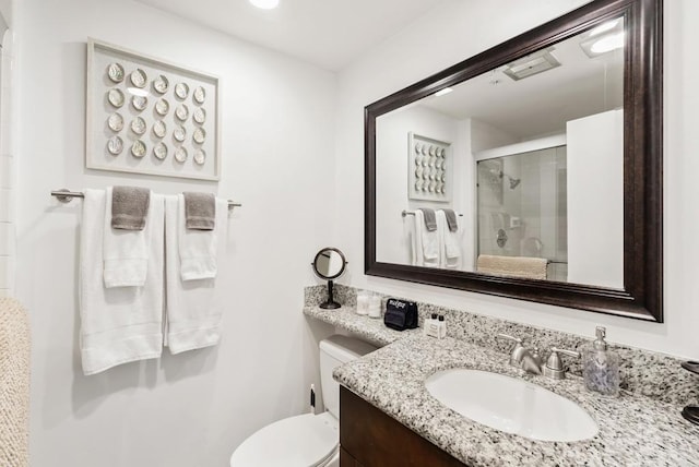 bathroom featuring toilet, a shower with shower door, and vanity
