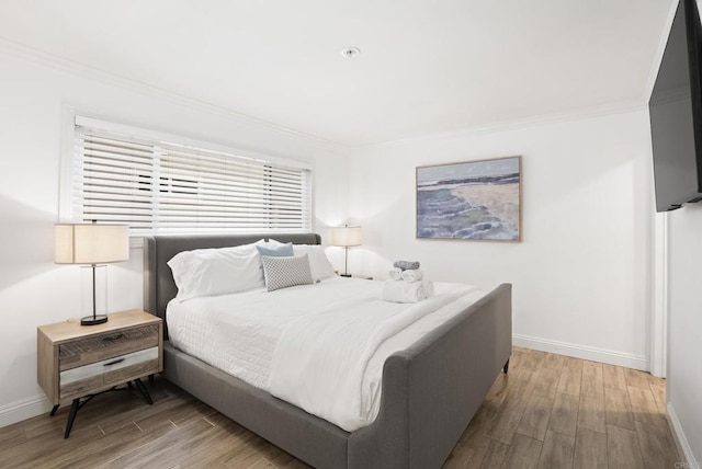 bedroom with crown molding, baseboards, and wood finished floors