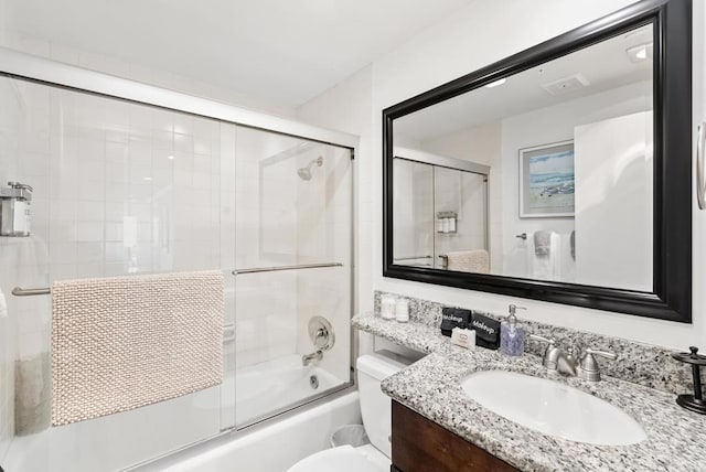 full bathroom featuring toilet, combined bath / shower with glass door, and vanity