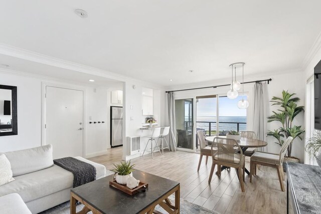 living area with recessed lighting, ornamental molding, light wood-style flooring, and a water view