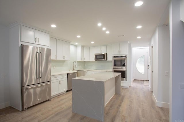 kitchen featuring light wood-style flooring, white cabinets, tasteful backsplash, and stainless steel appliances