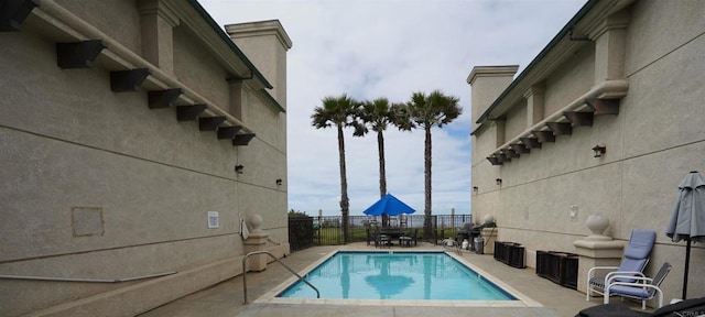 pool featuring grilling area, a patio, and fence