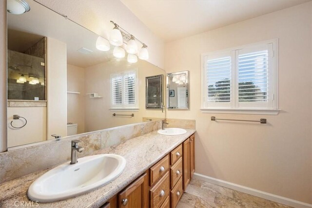 bathroom featuring baseboards, a sink, toilet, and tiled shower