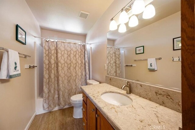 full bathroom featuring visible vents, vanity, wood finished floors, toilet, and shower / bath combo