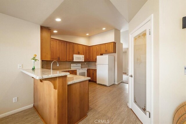 kitchen featuring brown cabinetry, a peninsula, white appliances, light stone countertops, and tasteful backsplash