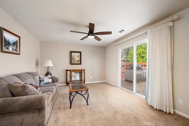 living area featuring light colored carpet, a ceiling fan, visible vents, and baseboards