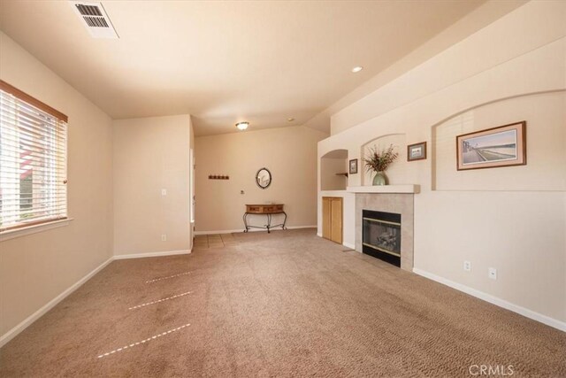 unfurnished living room with visible vents, a fireplace, vaulted ceiling, baseboards, and carpet