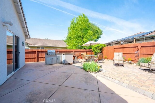 view of patio with area for grilling, exterior kitchen, and a fenced backyard