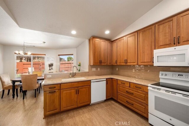 kitchen featuring a sink, white appliances, a chandelier, brown cabinetry, and light wood-style flooring