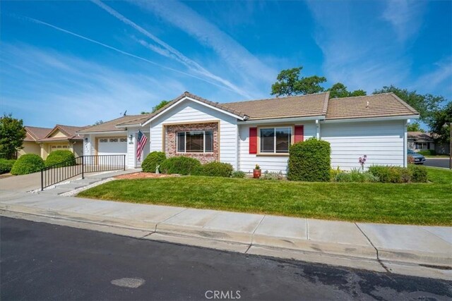 ranch-style house with a tiled roof, driveway, a front yard, and a garage