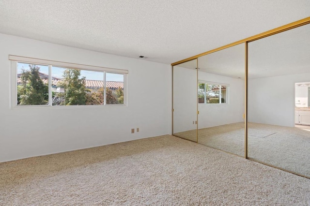 unfurnished bedroom with carpet, a closet, a textured ceiling, and visible vents