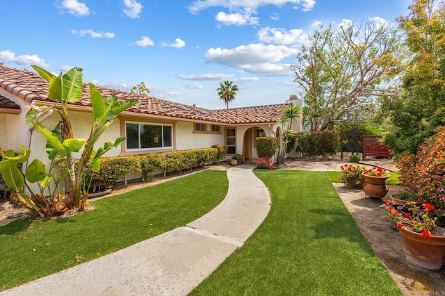 mediterranean / spanish house with a tiled roof, stucco siding, and a front lawn