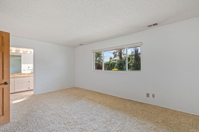 unfurnished bedroom featuring visible vents, connected bathroom, a textured ceiling, and light colored carpet
