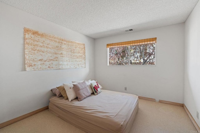bedroom with carpet floors, baseboards, a textured ceiling, and visible vents