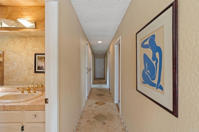 hall featuring a sink, recessed lighting, and a textured ceiling