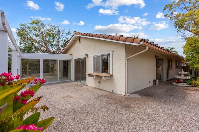 back of property with a patio, stucco siding, a tile roof, and fence