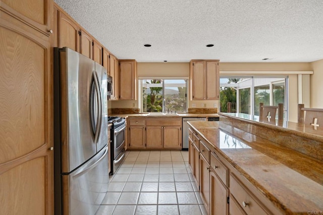 kitchen with light tile patterned flooring, recessed lighting, a textured ceiling, a sink, and appliances with stainless steel finishes
