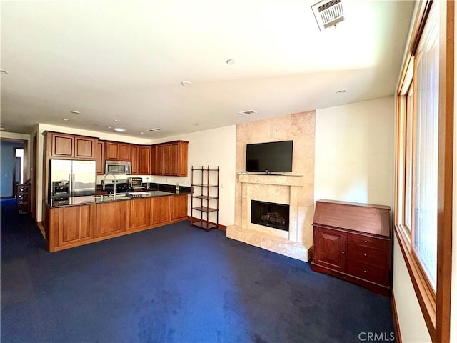 344 Triana Ln Unit 102, Avalon, CA 90704 - kitchen with open floor plan, stainless steel appliances, dark countertops, dark carpet, and a premium fireplace